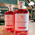 Two bottles of Rhubarb & Raspberry gin chin on a bar counter with a blurred bar background.