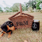Dog next to a wicker picnic basket and 'GIN & CHIN' insulated tumbler in a grassy outdoor setting