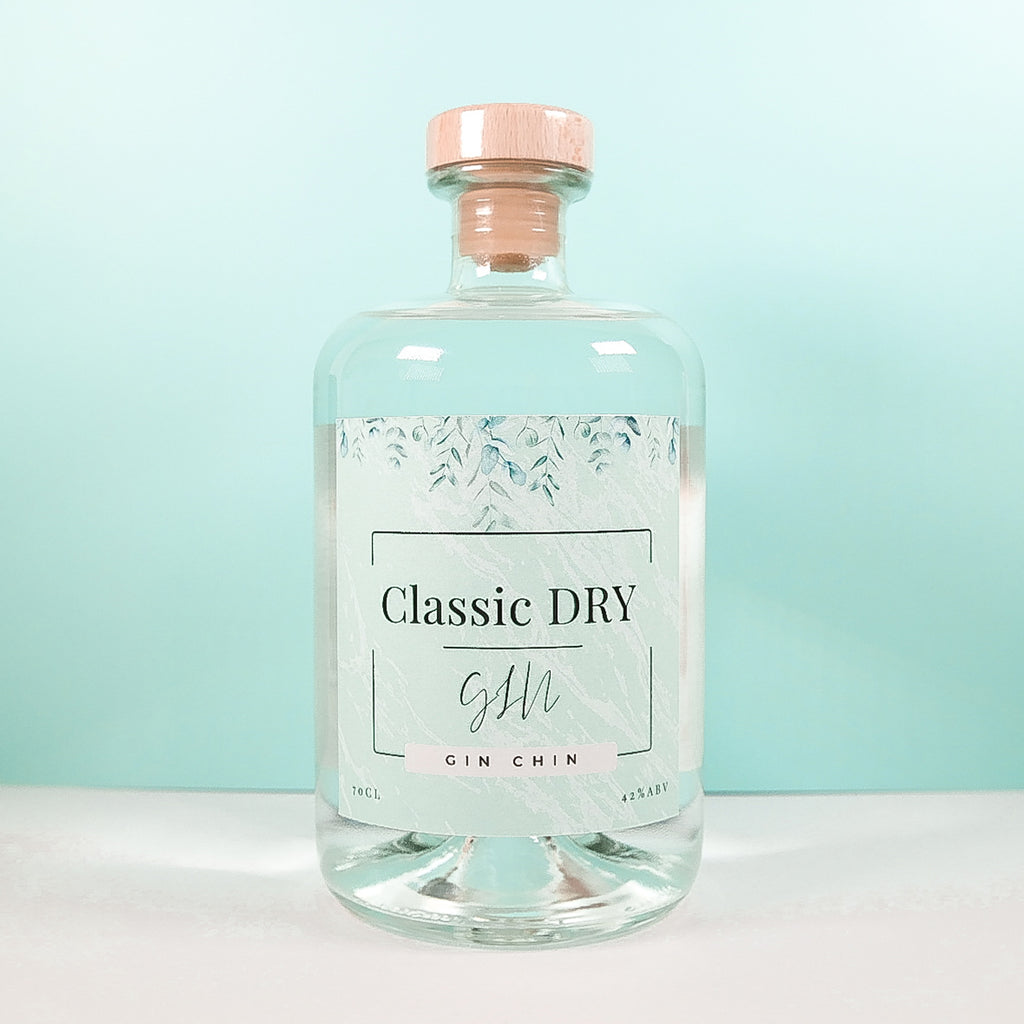 Clear glass bottle of Classic Dry Artisan Gin 70cl on a light blue background
