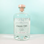 Clear glass bottle of Classic Dry Artisan Gin 70cl on a light blue background