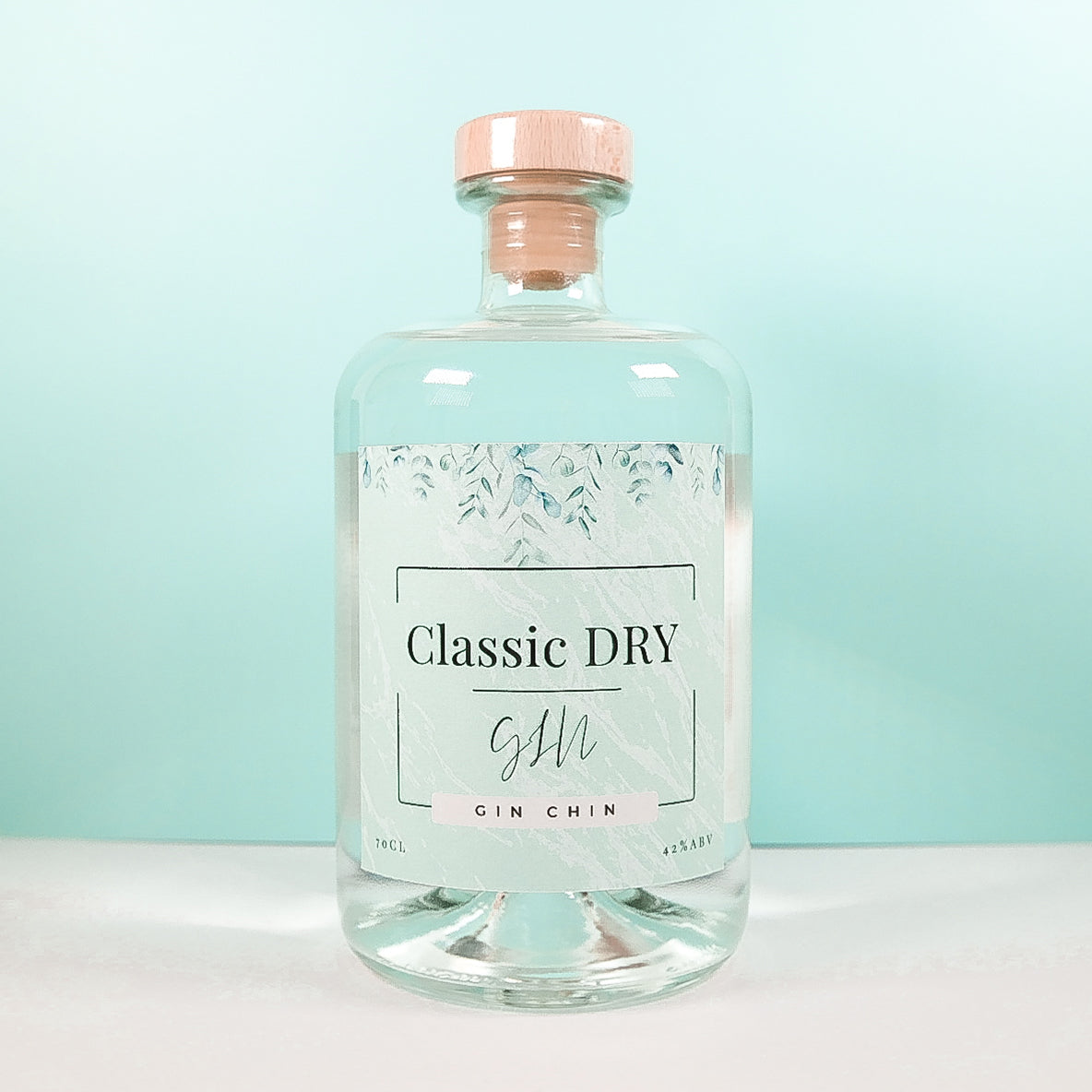 Clear glass bottle of Classic Dry Artisan Gin 70cl on a light blue background