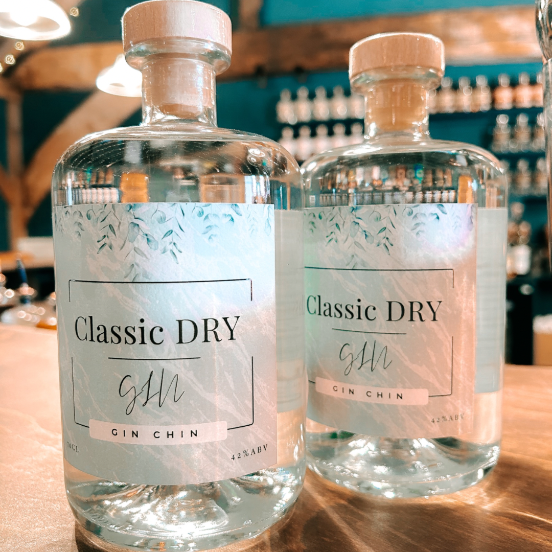Two bottles of 'Classic Dry' Gin Chin artisan gin on a bar counter with a blurred bar background.