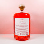 Bottle of Gin Chin Rhubarb and Raspberry artisan gin with a white label on a pink background