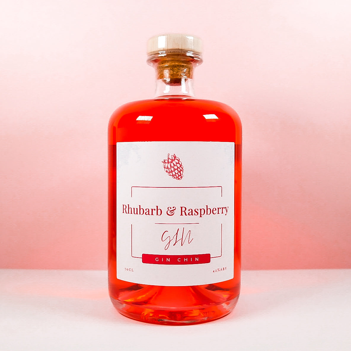 Bottle of Gin Chin artisan Rhubarb & Raspberry Gin on a pink background