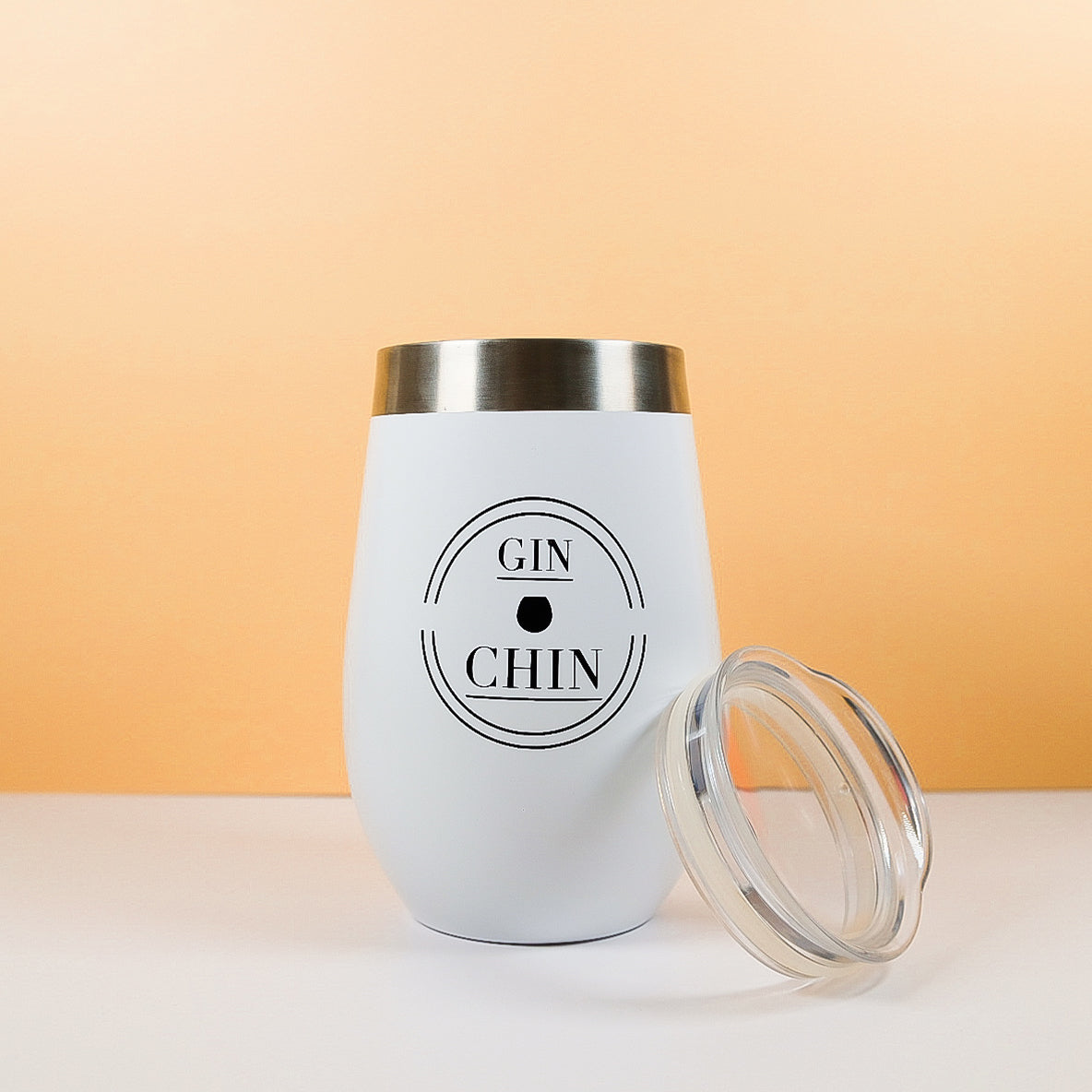 White gin tumbler with 'GIN & CHIN' text on a peach background