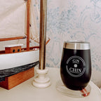 Black travel tumbler with 'GIN CHIN' text on a table with decorative background