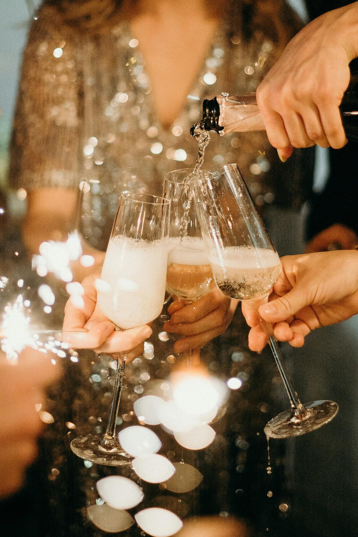 People toasting with champagne glasses and sparklers at a festive event.