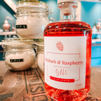 Bottle of Gin Chin small batch Rhubarb & Raspberry Gin on a wooden surface with jars in the background.