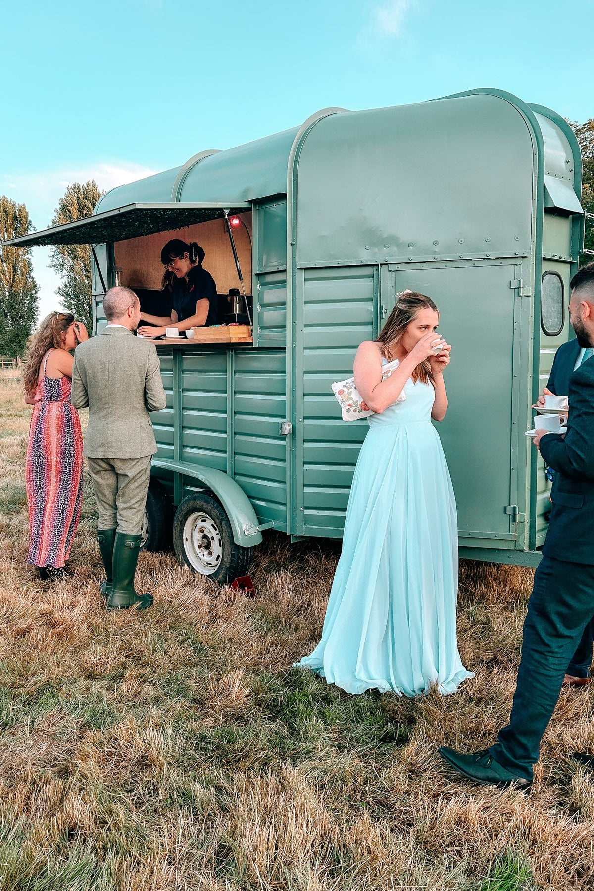 People interacting with a vintage-style wedding bar in an outdoor setting